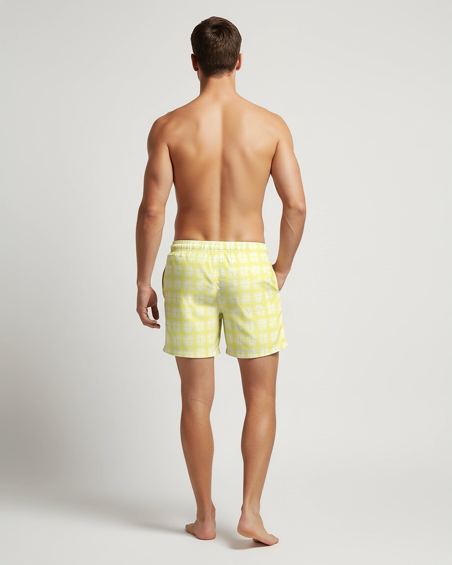 Full back view of Man wearing pastel yellow plaid swim shorts on a white background by PARADIS SVP