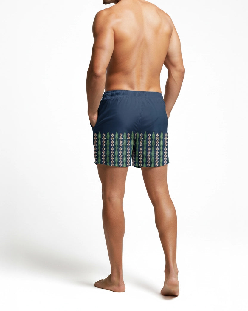 Back full View of Man wearing navy blue with green, yellow and pink pattern of leaves and flower swim shorts on a white background by PARADIS SVP