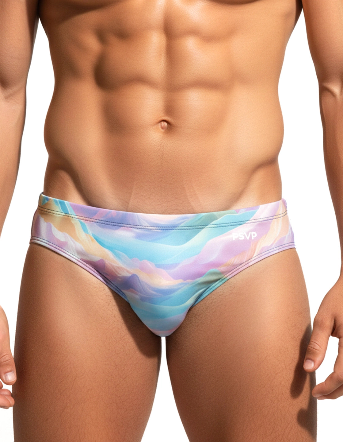 Close-up front view of a male model wearing a speedo-style swim brief with a pastel mountain-scape inspired pattern (blue, cyan, yellow, purple, pink and green) on a white background by PARADIS SVP