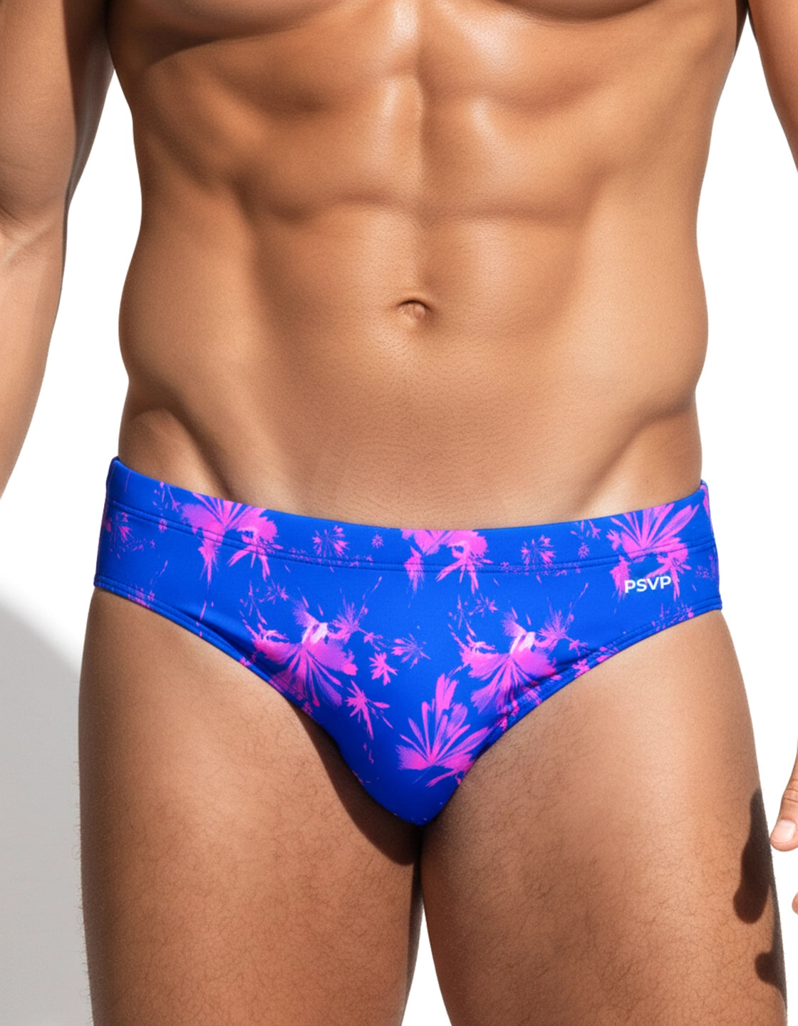 Close-up Front view of male model in a blue and pink floral pattern speedo-style swim brief on a white background by PARADIS SVP